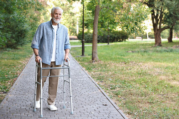 Senior man with walking frame in park, space for text