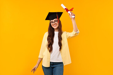Happy student with laptop and diploma after graduation on orange background