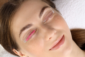 Woman undergoing eyelash laminating procedure in beauty salon, closeup