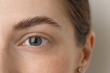 Young woman with beautiful eyes on light background, closeup
