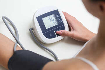 Woman checking blood pressure at home with a digital monitor. Heart health monitoring and cardiac care. Early diagnosis for preventing heart disease and maintaining well-being.