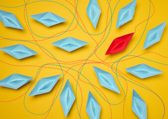 Paper boats on a yellow background with paths of movement, representing the concept of individuality