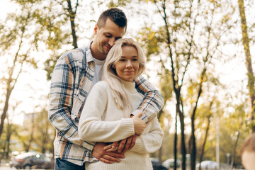 Fototapeta premium Portrait of beautiful woman and man hugging together standing in the park outdoors looking at camera