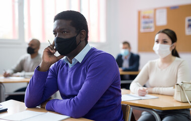 Confident adult African American in protective mask studying during refresher course. New life...