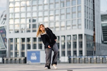 Young woman dancing in urban setting with modern architecture in background