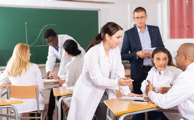 Portrait of adult medical students divided into small groups to discuss course material in classroom
