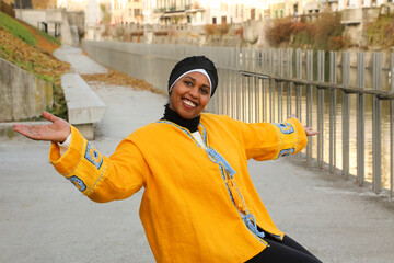 A laughing and smiling black woman in yellow ethnic clothing shows with her whole appearance that she is happy to see you.