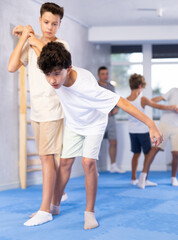 Fototapeta premium Sedulous underage practitioner of self-defense courses applying arm twist on his opponent in standing position