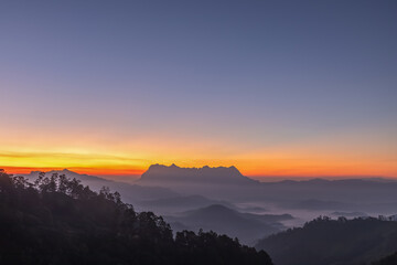 Obraz premium Early morning colourful sunset sky glowing over silhouetted mountains on the landscape