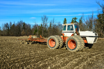 Fototapeta premium tractor and harrrow on the edge of a recently tilled field in the ottawa valley in fall room for text