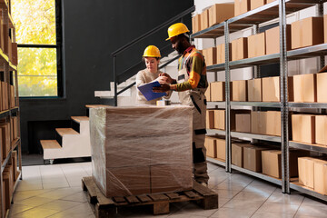Fototapeta premium Stockroom colleagues checking merchandise quality control report before start working at customers order in warehouse. Diverse storehouse employees preparing packages for delivey in storage room