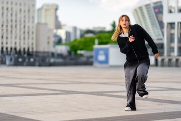 Young woman running on urban plaza during daytime with city backdrop
