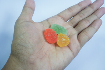 Holding CBD gummy candy on white background