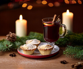 A cozy Christmas atmosphere with mince pies, a sprig of pine, and hot mulled wine in the background, accompanied by candles. Perfect for capturing family traditions and festive warmth.
