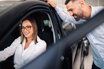 Friendly interaction as salesman discusses car with customer.
