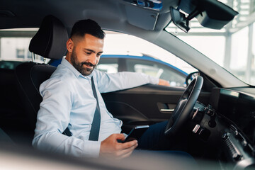 Man checks his phone excitedly after securing new car purchase.