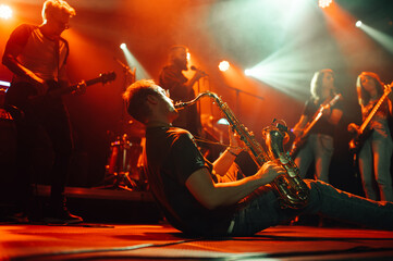 Saxophonist sitting on stage playing saxophone during live music concert