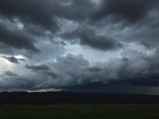 Dramatic storm clouds gathering over a dark and moody landscape, nature, weather