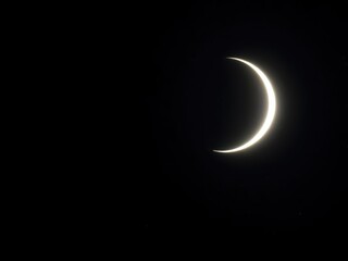 A serene image of a crescent moon shining brightly in the dark night sky, surrounded by twinkling...