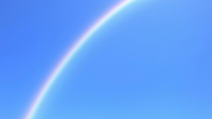 Vibrant rainbow stretching across a clear blue sky, colorful, vibrant