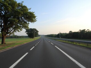 Fototapeta premium Empty highway surrounded by lush green park with clear blue sky above, green park, beautiful sky