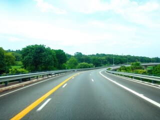 Empty asphalt road winding through a lush green park under a clear blue sky, sky, environment