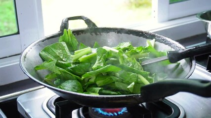 Slow motion footage of cooking, stir-frying vegetables in a pan in the kitchen. Fresh, organic green vegetables that help maintain the body. Garden vegetables. Cooking with heat. Video menu for lunch 