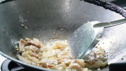 Slow motion footage of frying beef, pork for cooking in the kitchen. Home cooking. Stir frying beef, cooking with heat from a gas stove.