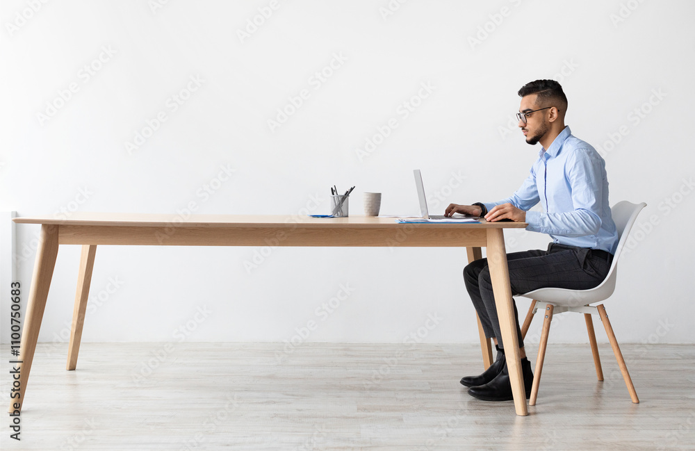 Poster profile side view portrait of focused middle eastern male manager in glasses working on laptop compu
