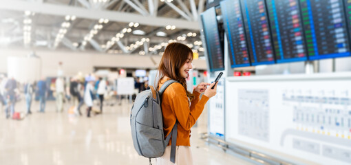 Young asian woman in international airport, using mobile smartphone and checking flight at the...