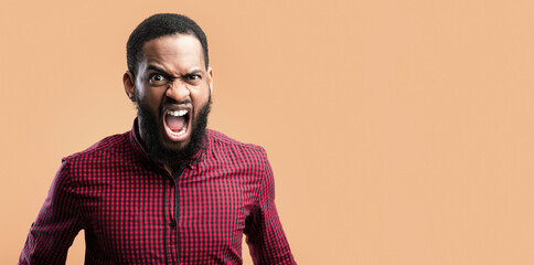 Obraz premium Anger Concept. Closeup headshot of furious black guy screaming, looking at camera over yellow wall