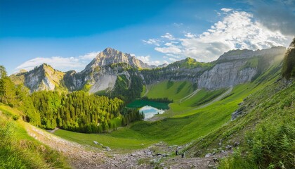 Fototapeta premium Mountain panorama with green valley, snow-capped peaks, and cloudy sky