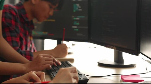 Slow motion back end software developer engineer for computer programming working together on debugging writing computing code, solving complex algorithms display on monitor in office. Burgeoning