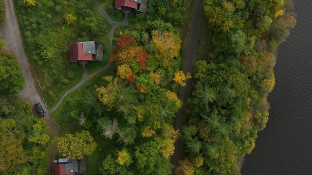 CAB&Uuml; by the Lakes, Killykeen Forest Park, County Cavan, Ireland, October 2023. Drone in Bird's Eye view tracks above wooden buildings and walking paths connecting cabins to lake shoreline and trail.