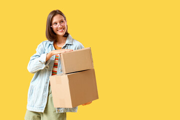 Beautiful young happy woman with parcels on yellow background