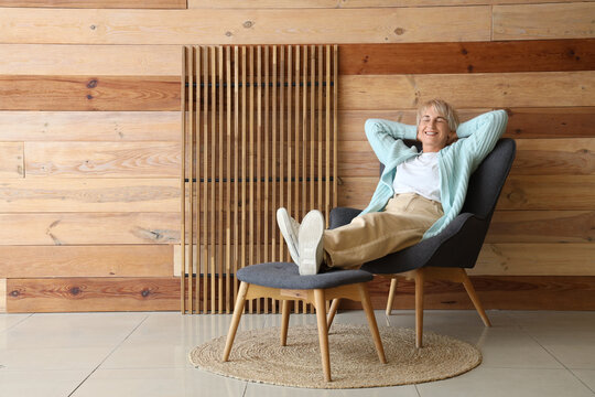 Old woman resting in armchair with legs on footstool at home