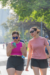 Obraz premium Two young Latina women walking outdoors while checking smartphone