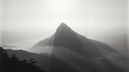 Fototapeta premium Majestic Mountain Peak Emerges Through Morning Fog with Golden Sunlight Breaking Through