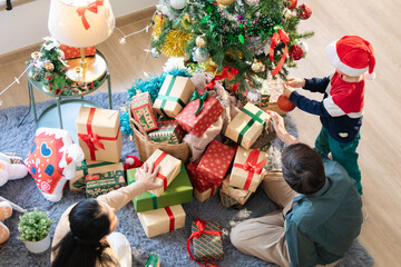 Happy Asian grandparents spend a holiday together with kid decorating Christmas tree and Xmas ornaments in domestic living room, grandma and grandfather celebrating festive season with grandchild