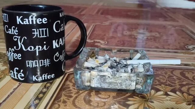 Mug and cigarette contdown to fall from ashtray
