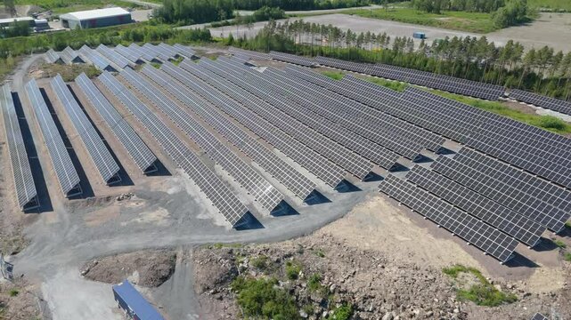 Aerial orbit left and rise to tilt down over Solar Farm with bifacial panels and renewable energy production, gravel spread throughout development