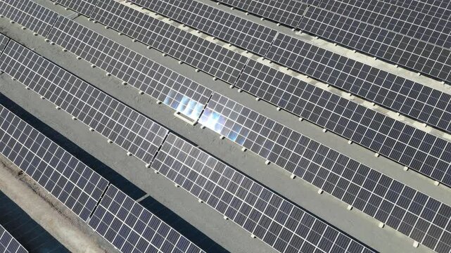 Aerial pan showcasing bifacial solar panels at Solar Farm in Finland, renewable energy, sunlight glistens and shines, gravel between rows