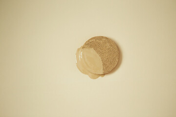 Liquid foundation makeup cream on cushion puff on beige background
