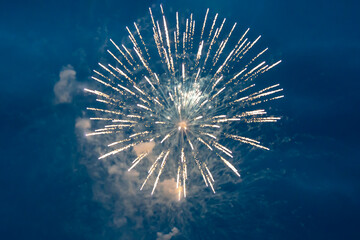 A magnificent ball of yellow fireworks against the black sky.