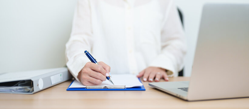 Asian woman working with computer laptop, female businesswoman reading and writing report or sign contract with documents folder stack at home or office. business financial concept