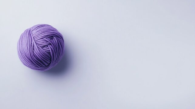 Vibrant purple yarn ball on a clean white backdrop, showcasing a minimalist aesthetic ideal for crafting and knitting projects.