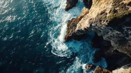 Aerial view of rugged cliffs and ocean waves crashing against the shore