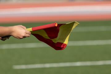 Assistant Referee Holding Red and Yellow Flag on Soccer Field