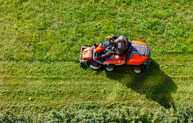 A person operating a lawn mower in a park, cutting the grass.