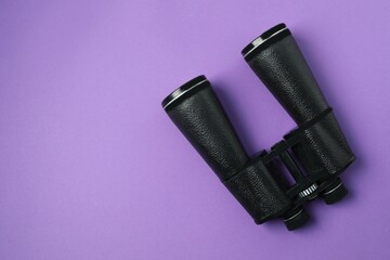 Black binoculars on color background. Top view